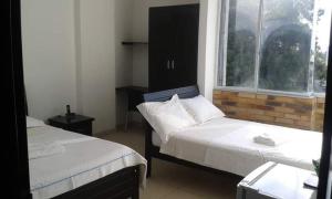 two beds in a room with a window and a bedskirts at Hotel Canacabare Plaza in Yopal