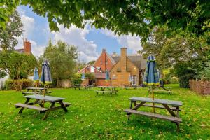 a group of picnic tables with umbrellas in a park at The Red Lion in Northampton