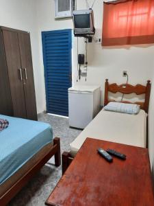 Habitación con 2 camas, mesa y TV. en HOTEL TROPICAL, en Cuiabá