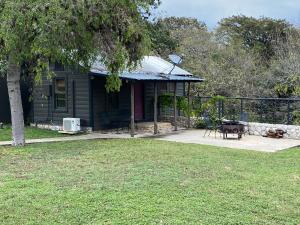 ein kleines grünes Haus mit einem Tisch und einem Zaun in der Unterkunft The Springs Retreat in Leakey