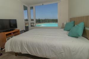 um quarto com uma cama grande e uma televisão em Departamento con Laguna artificial en Las Cruces em Valparaíso