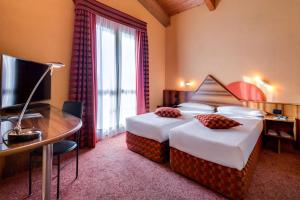 a hotel room with two beds and a desk and a television at La Villa - Sure Hotel Collection by Best Western in Ivrea