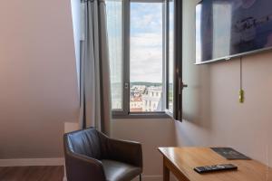 een kamer met een stoel, een bureau en een raam bij Hôtel Versailles Chantiers in Versailles