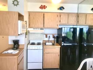 a kitchen with a black refrigerator and a sink at Coastal Sands - Ocean View at Symphony Beach Club! in Ormond Beach