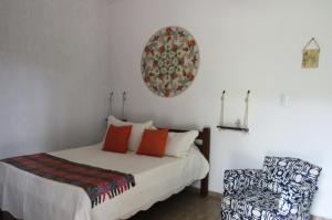 a bedroom with a bed and a chair at Pousada Erva Doce in Monte Alegre do Sul