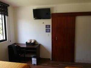 a room with a desk and a television on the wall at Chapelet Hostal in Tababela
