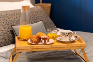 a tray of breakfast foods and orange juice on a bed at Host inn Lyon - Hypercentre Vieux Lyon in Lyon