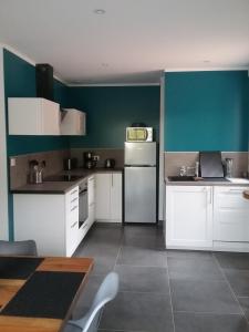 a kitchen with white cabinets and a green wall at Maison Lulalilo in Crémeaux