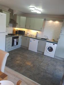 cocina con armarios blancos, lavadora y secadora en Home from Home 3 bedroom pier front stay, en Donaghadee