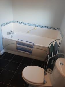 a bathroom with a white tub and a toilet at Home from Home 3 bedroom pier front stay in Donaghadee +15 photos