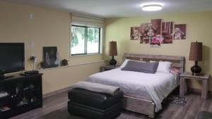 a bedroom with a bed and a chair and a television at Sacred Pilgrimage Studio in Metchosin