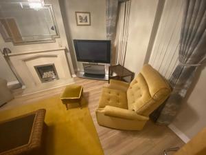 a living room with a yellow chair and a television at Home from Home 3 bedroom pier front stay in Donaghadee