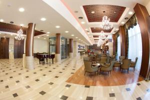 a lobby with a restaurant with chairs and tables at Metropolis Hotel in Bistriţa