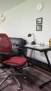 a desk with a red chair and a desk with a computer at Sacred Pilgrimage Studio in Metchosin