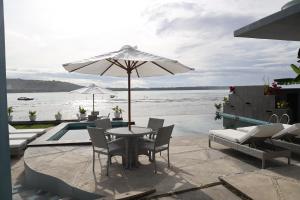 un patio con mesa, sillas y sombrilla en Grace Wave Resort, en Hilibotodane