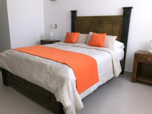 una camera da letto con un letto grande con una coperta arancione di Figaro Hotel Samana a Santa Bárbara de Samaná Altre 37 foto