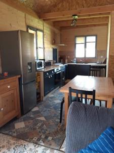 a kitchen with a wooden table and a kitchen with a refrigerator at Chalet chaleureux avec parking garage motos, vélos in La Chapelle-aux-Chasses