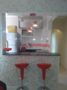 eine Küche mit roten Hockern vor einer Theke in der Unterkunft Vista em Frente ao Mar em Guilhermina in Praia Grande
