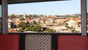 einen Blick auf die Stadt von einem Fenster mit zwei Stühlen in der Unterkunft Panoramic City View Apartment - Guimarães in Guimarães