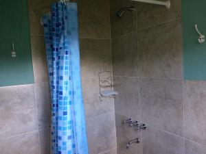 a shower with a blue glass shower curtain at Cabañas Lofts de Caminos al Ser in Capilla del Monte