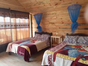 Un dormitorio con dos camas en una cabaña de madera. en cabañas liquidambar, en La Trinitaria