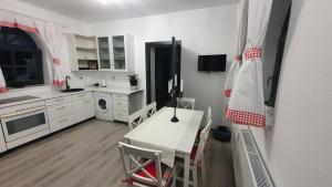 a kitchen with a white table and a table and chairs at Casa mica Resita in Reşiţa