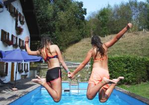 two girls jumping into a swimming pool at Ferienhof Mühlthal in Edling