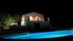 una casa iluminada por la noche con una piscina en Más del Sandungo en Els Ibarsos