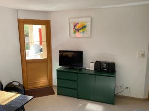 a room with a green dresser with a television on it at Casa Selva 2000 Fl Whg Nr 2 in Lenzerheide