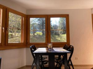 a dining room with a table and two windows at Casa Selva 2000 Fl Whg Nr 2 in Lenzerheide