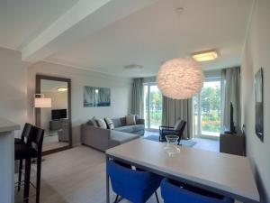 ein Wohnzimmer mit einem Tisch und blauen Stühlen in der Unterkunft Dünenresidenz Prora - Ferienwohnung mit Meerblick, 1 Schlafzimmer und Balkon NP-312 in Binz