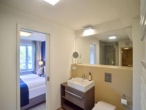 ein Badezimmer mit Waschbecken, Bett und Spiegel in der Unterkunft Dünenresidenz Prora - Ferienwohnung mit Meerblick, 1 Schlafzimmer und Balkon NP-312 in Binz