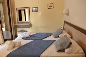 two beds in a hotel room with a mirror at Vassilis Studio's in Perivólion