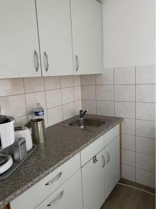 a kitchen with white cabinets and a sink at Olgas Ferienwohnung Saarburg Bahnhofstraße 13G in Saarburg