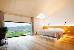 a bedroom with a bed and a large window at Tavarneta Estate in Dobrovo