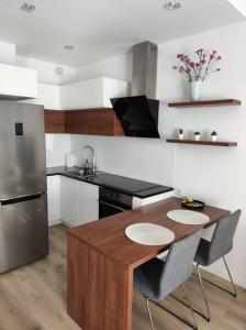 Branickiego 23 Apartment close to Medicover and Paley في وارسو: مطبخ مع طاولة خشبية وثلاجة حديد قابلة للصدأ