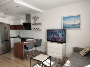 a kitchen and a living room with a table and a tv at Branickiego 23 Apartment close to Medicover and Paley in Warsaw