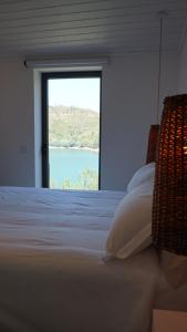 a bedroom with a large window looking out at the water at Zab Living in Vila de Rei