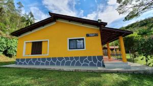 una pequeña casa amarilla con porche en Chacara Ceara en Monte Alegre do Sul