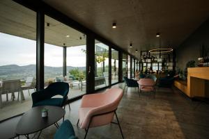 een restaurant met stoelen, tafels en ramen bij Tavarneta Estate in Dobrovo