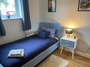 a bedroom with a blue bed and a night stand at Lime Tree Apartment in Coventry