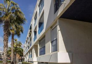 a white building with blue windows and a palm tree at Miracle Morning in La Grande Motte