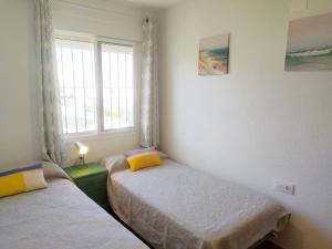 two twin beds in a room with a window at Gran adosado de esquina muy cerca de la playa en la Antilla in Huelva