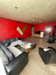 a living room with red walls and black leather furniture at Vilhelmov’s apartament in Lukovit