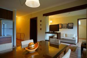 a living room with a dining table and a television at Apartamento Lago Negro in Gramado