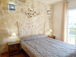 a bedroom with a bed and a stone wall at Gran adosado de esquina muy cerca de la playa en la Antilla in Huelva