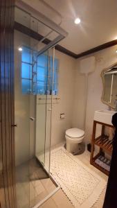 uma casa de banho com uma cabina de duche em vidro e um WC. em locanda cecchini em Campos do Jordão