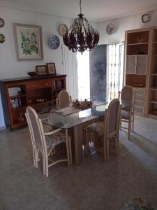 comedor con mesa, sillas y lámpara de araña en Casa La Gaviota con acceso privado a la playa, en Mazagón
