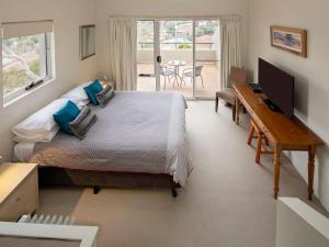 Un dormitorio con una cama y un escritorio con una computadora. en Cascades 18 3 Kurrajong Street, en Jindabyne