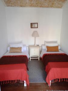a bedroom with two beds and a table with a lamp at Casa Tiradentes - Apto 2 in Tiradentes